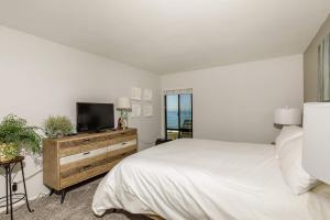 a bedroom with a bed and a flat screen tv at Oceanfront Sea'batical - SBTC212 in Solana Beach +34 photos