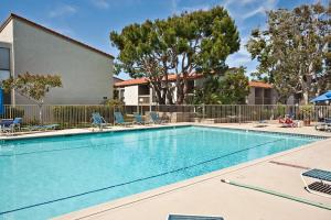 a swimming pool with chairs and a building and trees at Serenity By The Sea - SBTC202 in Solana Beach