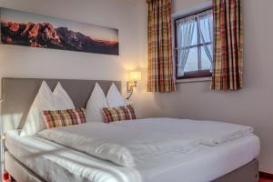 a bedroom with a large white bed with a window at Haus Hammerer in Ellmau