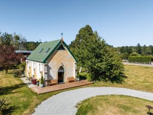 a small church with a green roof in a field at St Patrick's Church - Hawea Flat in Hawea Flat