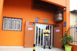 アビジャンにあるRésidence Vanestelleのオレンジ色の建物の前に立っている男性