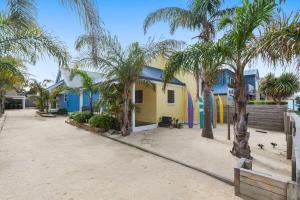 a yellow house with palm trees in front of it at #1 Dog friendly house OPPOSITE the BEACH in Torquay