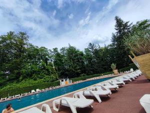 a row of white lounge chairs next to a swimming pool at Tiny Sweet Home - 3 nuits minimum in Saint-Chéron