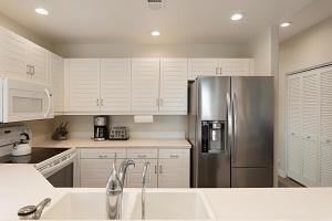 a kitchen with white cabinets and a stainless steel refrigerator at Trackside Tides - DM2925 in San Diego