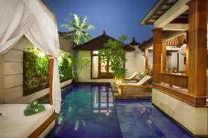 a villa with a swimming pool and a house at Astagina Resort Villa and Spa in Legian