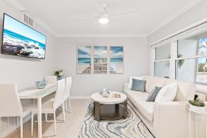 a living room with a white couch and a table at 100 Steps to beach access - 5 minute walk to the Village - Private Porch in Siesta Key