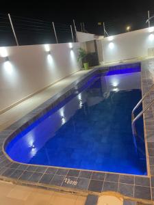 Una gran piscina con agua azul por la noche. en Villa Cissé, en Saly Portudal