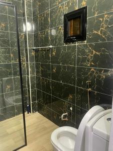 baño con aseo y pared de azulejos negros en Villa Cissé, en Saly Portudal