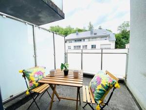 a balcony with a wooden table and two chairs at Airy and spacious 3 Bedroom w terrace&parking in Luxembourg