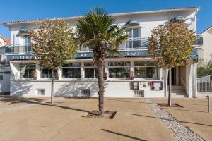 a palm tree in front of a hotel at Hôtel de la Plage in Saint-Palais-sur-Mer