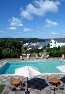 uma piscina com cadeiras e um guarda-sol em Merlewood Hotel em Saundersfoot