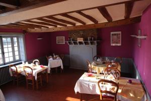 a dining room with tables and chairs and purple walls at Auberge Normande in Alençon
