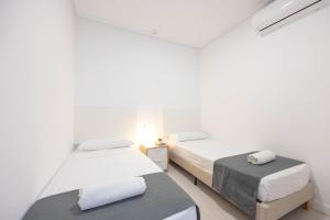 dwa łóżka w pokoju z białymi ścianami w obiekcie Apartamentos Marina Playa de Torrevieja by Apartamentos Torrevieja w mieście Torrevieja