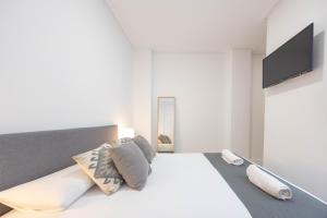 sypialnia z dużym białym łóżkiem z poduszkami w obiekcie Apartamentos Marina Playa de Torrevieja by Apartamentos Torrevieja w mieście Torrevieja