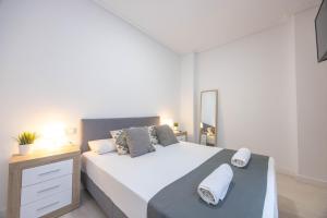 sypialnia z dużym łóżkiem, komodą i lustrem w obiekcie Apartamentos Marina Playa de Torrevieja by Apartamentos Torrevieja w mieście Torrevieja
