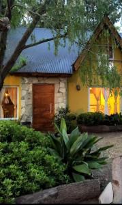 ein gelbes Haus mit einer Holztür im Hof in der Unterkunft Cabañas del Bosque in Santa Teresita