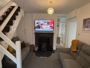 a living room with a couch and a flat screen tv at Cahir Cosy Cottage in Cahir