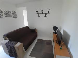 a living room with a couch and a television at Apartamento, 5 minutos da praia in Porto Belo