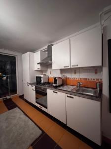 a kitchen with white cabinets and a sink at Apartament MaGiFa Constanța in Constanţa