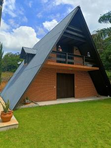 een persoon die uit het raam van een driehoekig huis kijkt bij Chalé Bem-Estar in Massaranduba