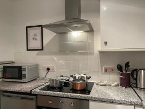 a kitchen with a stove and a microwave at Lovely 2 bedroom house in Bath with private parking garden WiFi & easy access to city centre in Bath