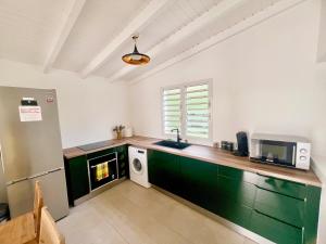a kitchen with a sink and a microwave at Cocon des îles in Anse-Bertrand