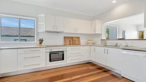 a white kitchen with white cabinets and a window at Sea Legs in Wooli