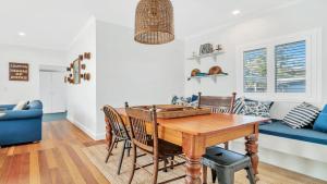 a dining room with a wooden table and a blue couch at Sea Legs in Wooli