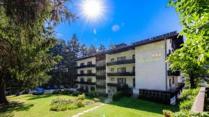 a building in a park with the sun in the sky at Parkhotel Zuzek in Sankt Kanzian