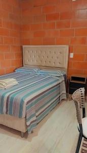 ein Bett in einem Zimmer mit einer orangefarbenen Ziegelwand in der Unterkunft "Suites Paraiso Tropical" in São Sebastião