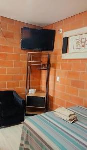 Zimmer mit einem Bett und einem Flachbild-TV in der Unterkunft "Suites Paraiso Tropical" in São Sebastião