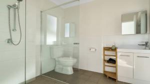 a white bathroom with a toilet and a shower at Wooli Waves in Wooli