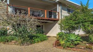a house with a balcony and plants in front of it at Wooli Waves in Wooli