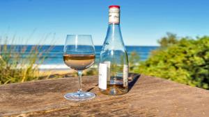 a glass of wine next to a bottle on a table at Wooli Waves in Wooli