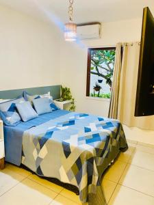 a bedroom with a bed with a blue and white comforter at Chalé Sertão e Mar in Canguaretama +26 photos