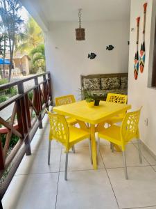 a yellow dining room table and chairs on a balcony at Chalé Sertão e Mar in Canguaretama