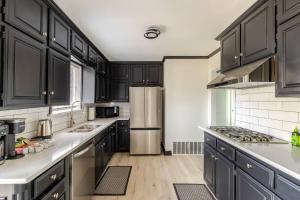 a kitchen with black cabinets and a stainless steel refrigerator at Cozy 3 Bedroom House Near DFW in Bedford