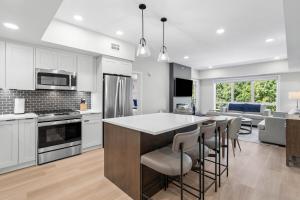a kitchen with white cabinets and a bar with stools at 2 bedrooms-3 beds 2 baths-Rocky Creekside Retreat - Top Floor - Heated Pool and Hot Tub in Dead Man's Flats