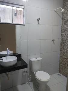 a white bathroom with a toilet and a sink at Casa para período de carnaval de caicó in Caicó