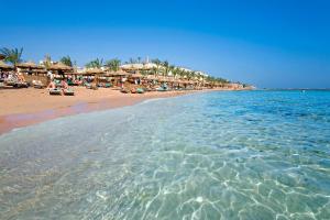 a beach with chairs and umbrellas and the water at Tamra Beach Resort in Sharm El Sheikh