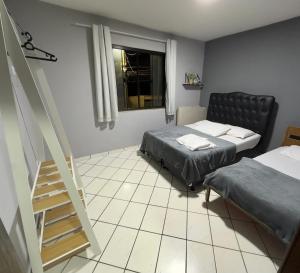 Habitación pequeña con 2 camas y escalera. en Amós Beach House, en Arraial do Cabo