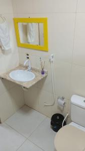 a bathroom with a sink and a mirror and a toilet at Kitnets casa Amarela Imbassai in Imbassai
