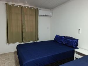 a bedroom with a blue bed and a window at Temporada Peterle | Casa vista mar Irirí in Anchieta