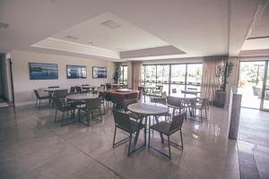 a dining room with tables and chairs and windows at Apartamento em Guarajuba - Condomínio Paraíso dos Coqueiro in Guarajuba