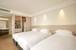 two beds sitting next to each other in a bedroom at Mayplace Hotel in Seoul