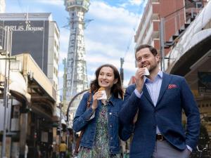 a man and a woman walking down a street eating ice cream at Hotel Gracery Osaka Namba in Osaka