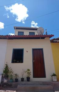 a white house with a brown door and some plants at Hospedagem Casa Da Lia in Lençóis