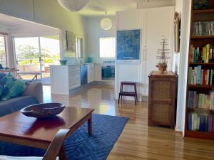 Una sala de estar con un sofá y una mesa y una cocina. en Unwind at Hyams Beach, en Hyams Beach