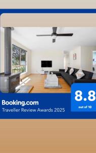 a living room with a black couch and a tv at Picturesque Lakeside Getaway: Views, Beach, Park in Loch Sport
