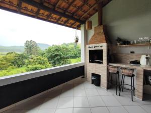 a kitchen with a fireplace and a large window at Kascata Complexo de Refúgio in Conceição dos Ouros